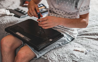 A young man is changing the thermal paste on a laptop.