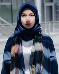 Portrait of confident young woman wearing hijab while standing in city