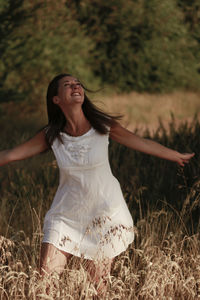 Beautiful woman standing amidst plants on field