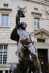 Low angle view of statue against building in city