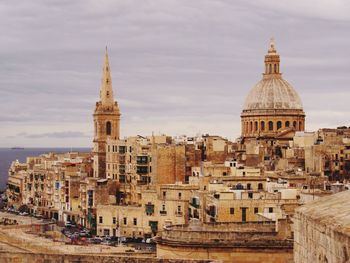 Buildings in city against cloudy sky