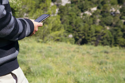 Midsection of man using mobile phone on field