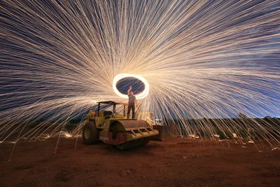 Man spinning wire wool while standing on bulldozer at beach