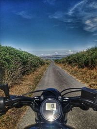 Empty road amidst field against sky