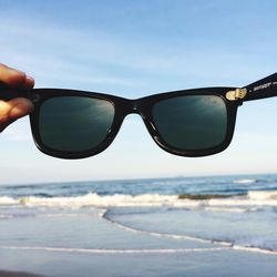 Close-up of sunglasses on beach against sky