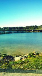 Scenic view of river and bridge in city against clear sky