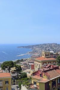 Town by sea against clear blue sky