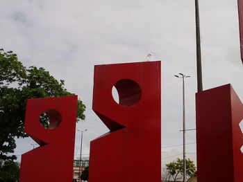 Low angle view of red and sign against sky