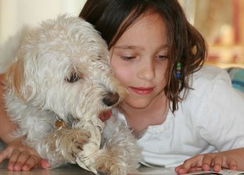 Portrait of girl with dog reading book at home