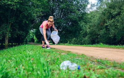 Full length of woman collecting garbage on field