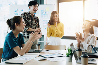 Happy business people applauding while meeting at desk