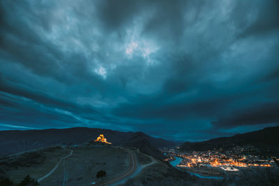 Cars on road against cloudy sky at night