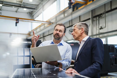 Manager pointing by businessman discussing at factory