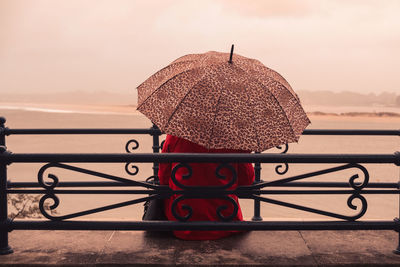 Close-up of hat on railing against sky during sunset