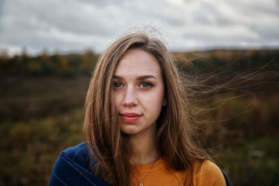 Portrait of beautiful young woman standing on field