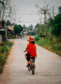 Rear view of man riding bicycle on road