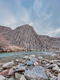 Rocks by lake against sky