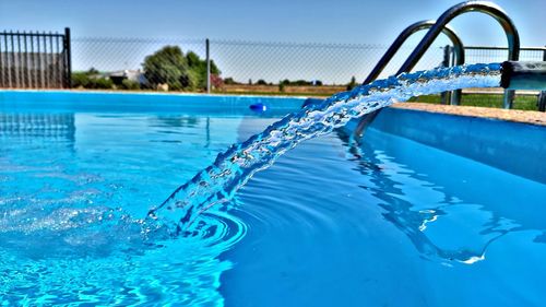 Water splashing in swimming pool against blue sky