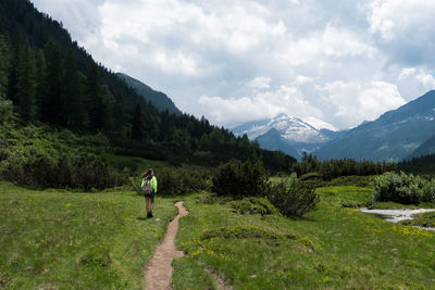 Rear view of woman hiking on mountain against sky