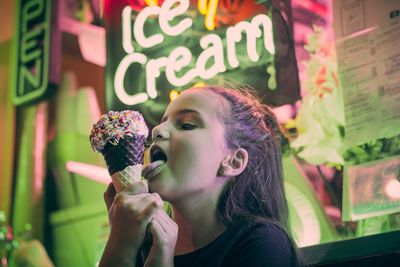 Close-up of girl eating ice cream cone in restaurant