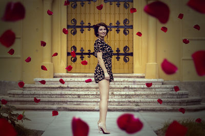 Portrait of woman standing against red wall