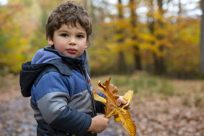 Boy holding leaves during autumn
