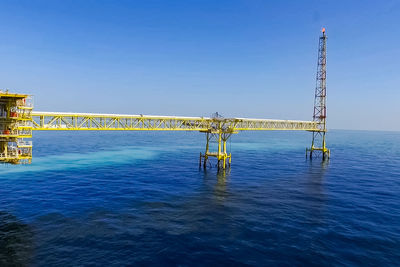 View of bridge over sea against clear blue sky