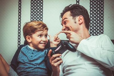 Smiling father and cute son playing video game at home