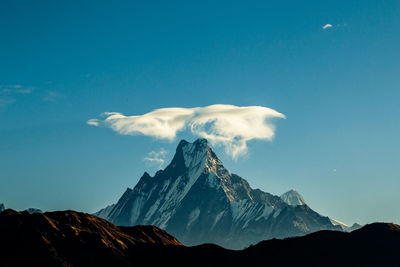 Low angle view of snowcapped mountains against blue sky