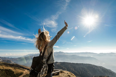 Woman with arms outstretched against mountain range