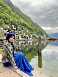 Portrait of  woman in blue dress sitting beside the hallstat lake with water reflection