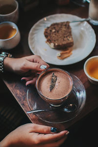 High angle view of woman holding coffee cup on table