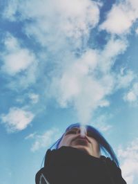 Low angle view of woman smoking against sky