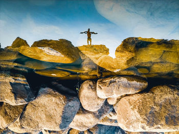 Man standing on rock against sky