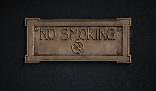 Close-up of no smoking sign on black wall