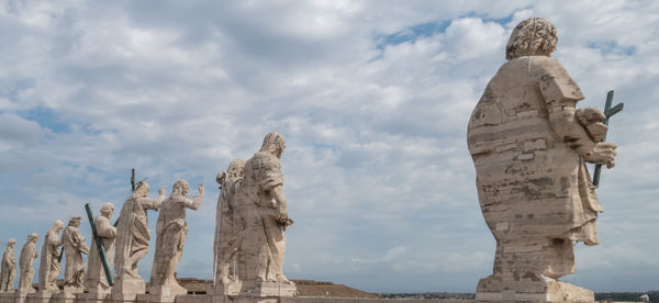 Low angle view of statues against cloudy sky