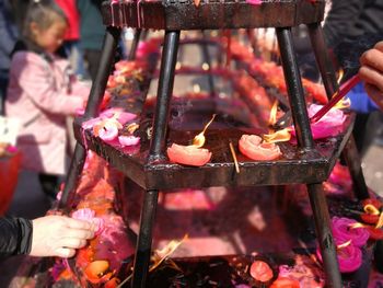 Midsection of man holding burning candles in temple