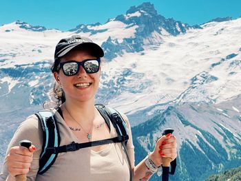 Portrait of young woman standing against snowcapped mountain