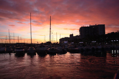 Fiery red and purple sunset on ibiza coast view from port at balearic sunset between boats