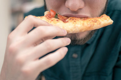 Midsection of man eating pizza