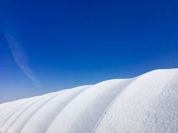 Low angle view of snowy field against clear blue sky