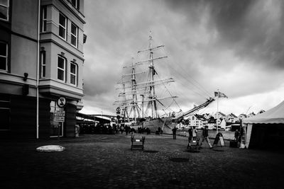 Sailboats in city by buildings against sky