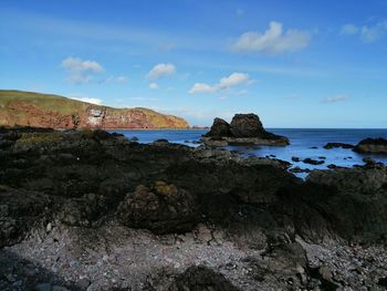 Rock formations on shore against sky