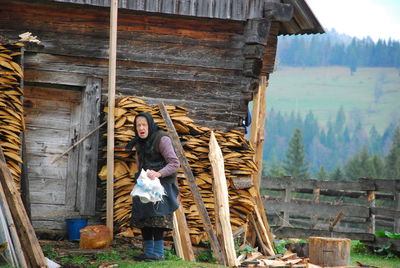 Senior woman standing by hut
