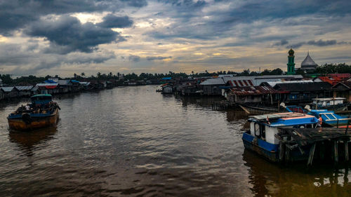 Boats moored in sea against sky during sunset