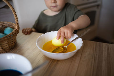 Close-up of cute baby boy holding bowl on table