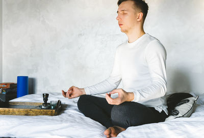 Young man looking away while sitting on table at home