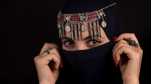 Midsection of woman holding eyeglasses against black background