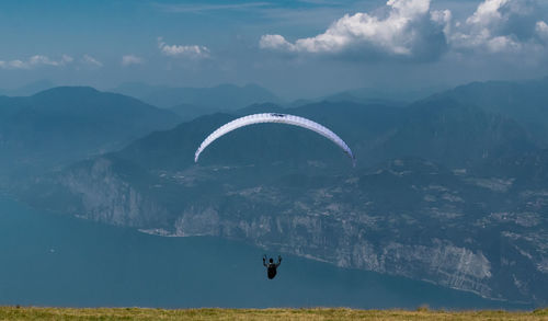 Man paragliding over mountain against sky