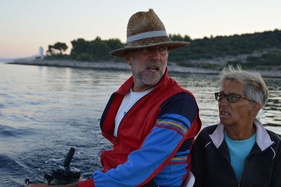 Mature couple boating in sea against sky